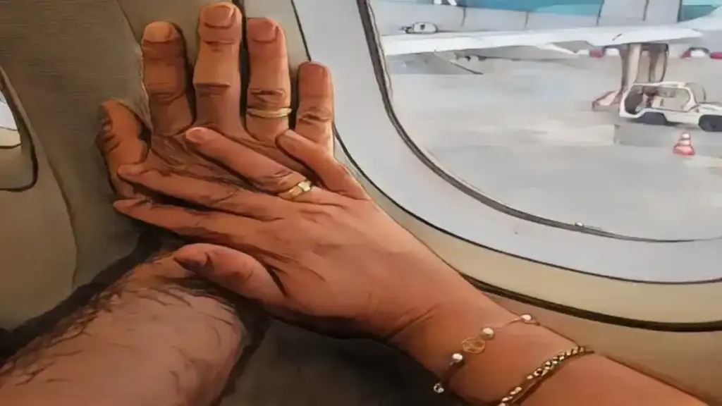 Valentine's Day Love Details (Spaniards VS Colombians) Valentine's Day love details for my wife: two hands with rings gently touch each other against the window of an airplane, symbolizing an intimate moment between a couple during their trip.
