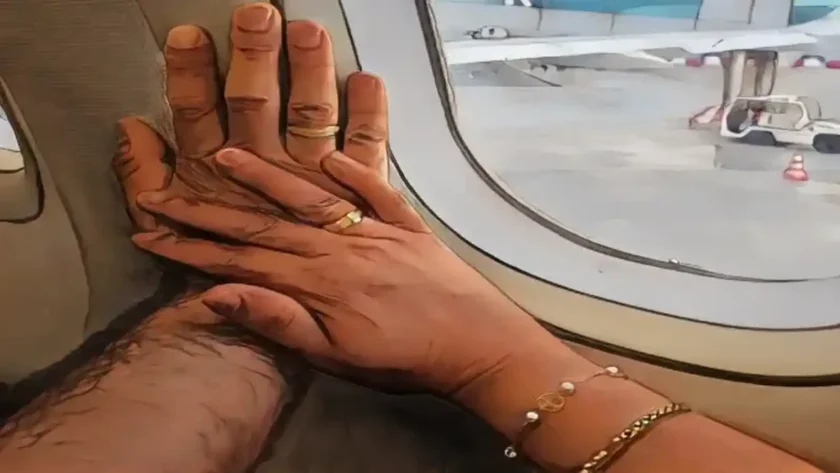 Detalles de amor en San Valentín para mi mujer: dos manos con anillos se tocan suavemente contra la ventana de un avión, simbolizando un momento íntimo de pareja durante el viaje.